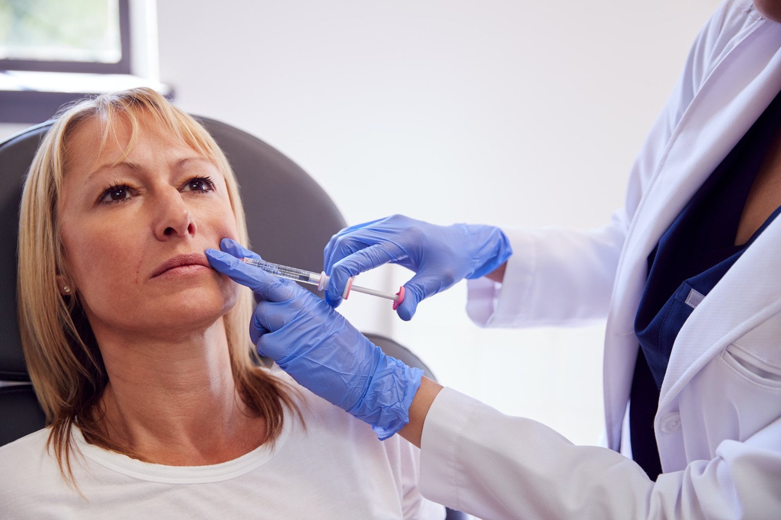 Mature Woman Sitting In Chair Being Give Botox Injection By Female Doctor